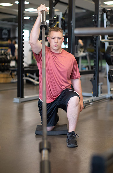 Athlete doing a half-kneeling landmine press with a barbell